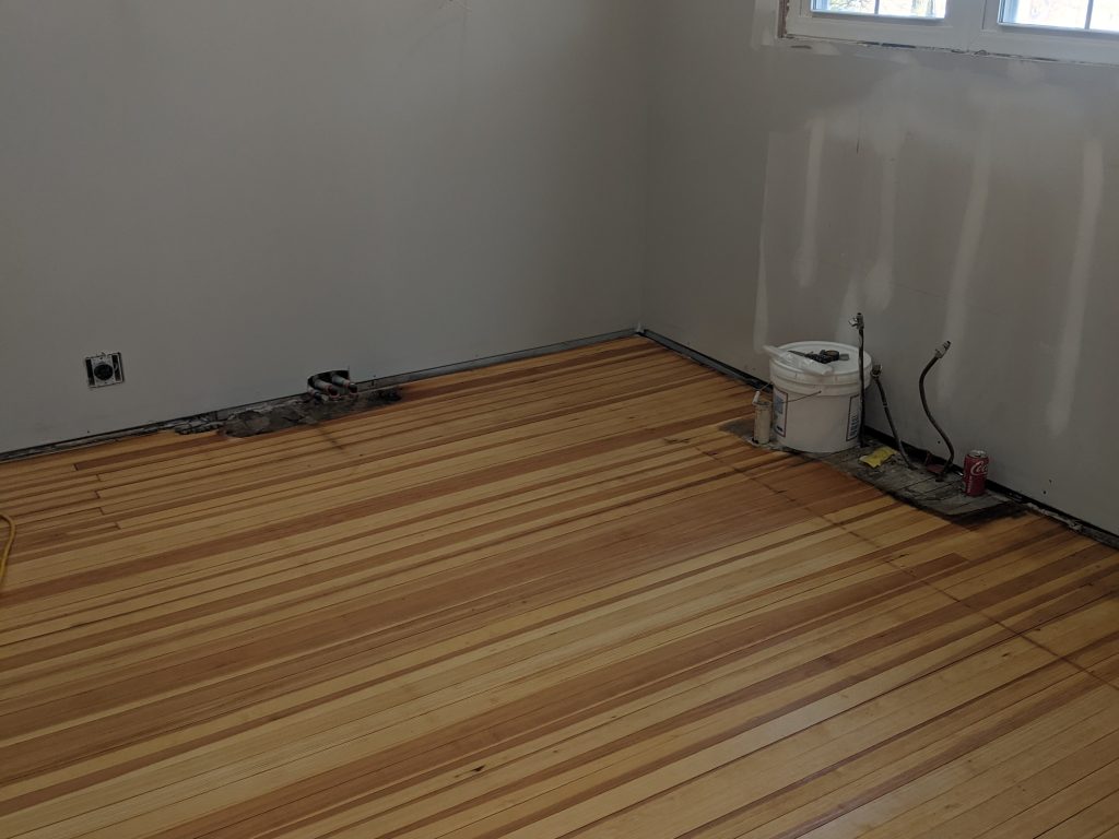A room with wood floors and a white wall.