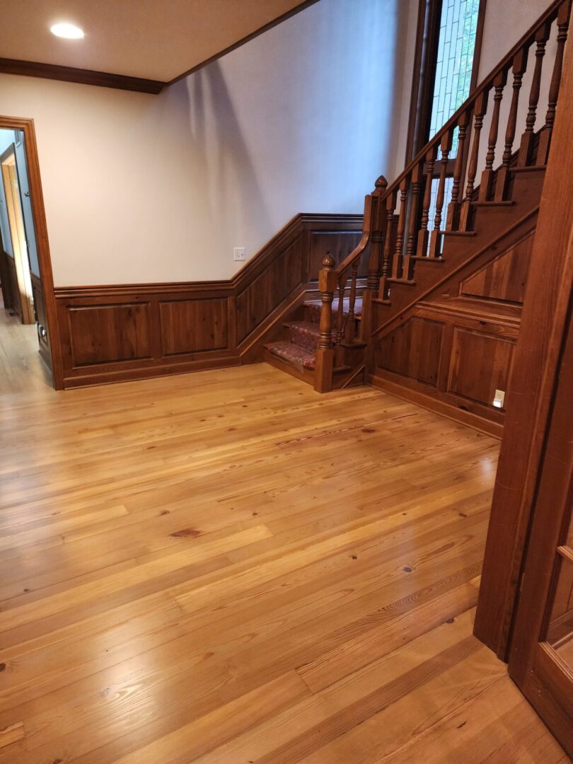 A wooden floor with stairs and wood paneling.