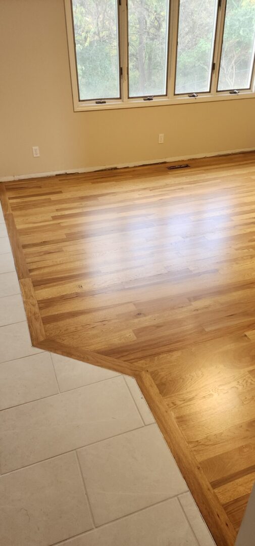 A wooden floor with a white tile wall.