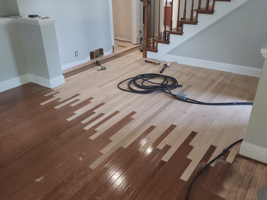 A room with wood floors and a hose on the floor.