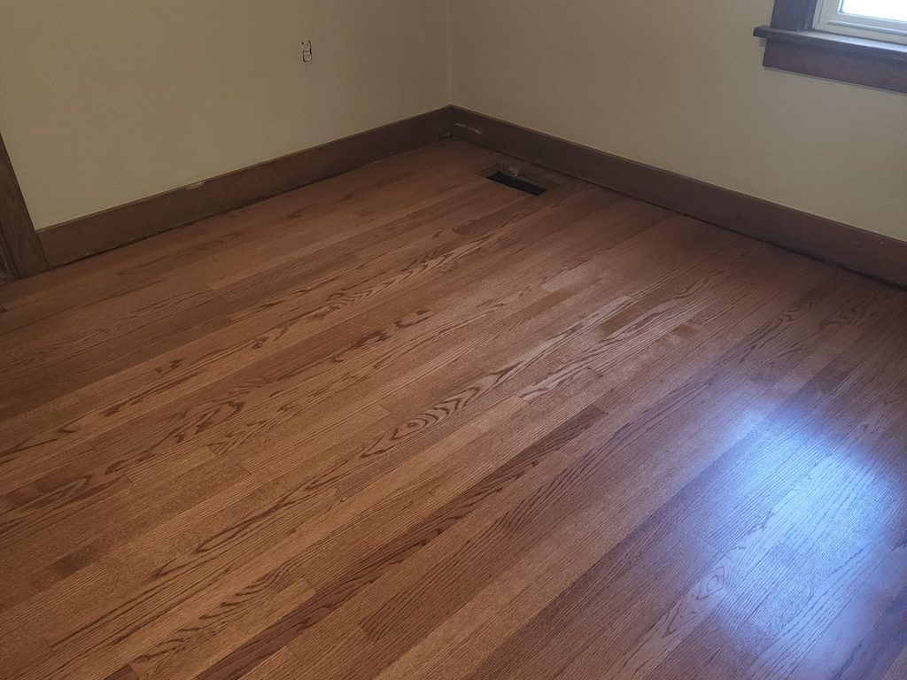 A room with wood floors and a cat on the floor.