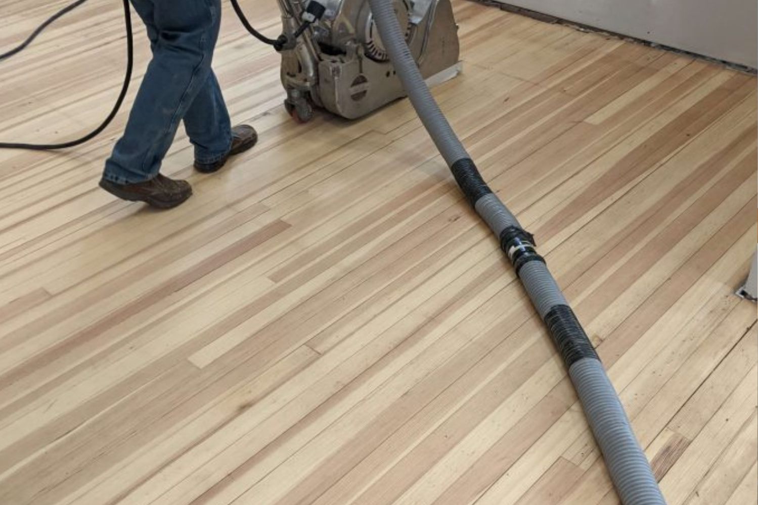 A person with a vacuum cleaning the floor.